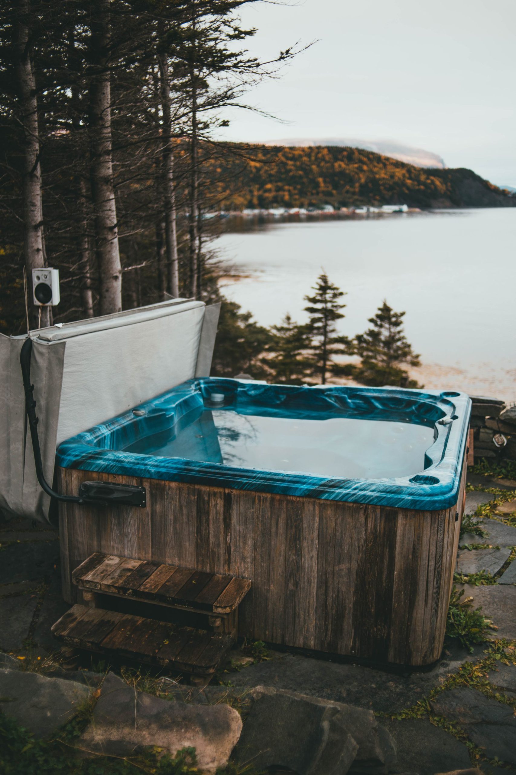 A wood-sided hot tub on a deck above a lake